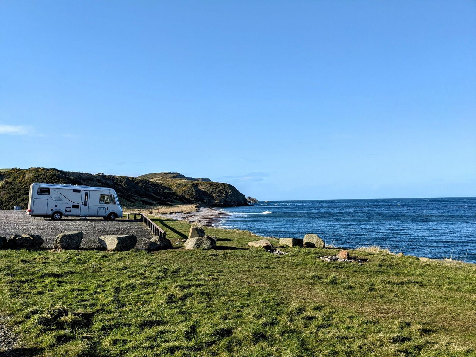 A motorhome parked on the grass above the beach at Aberdour Bay, the Moray Firth beyond.
