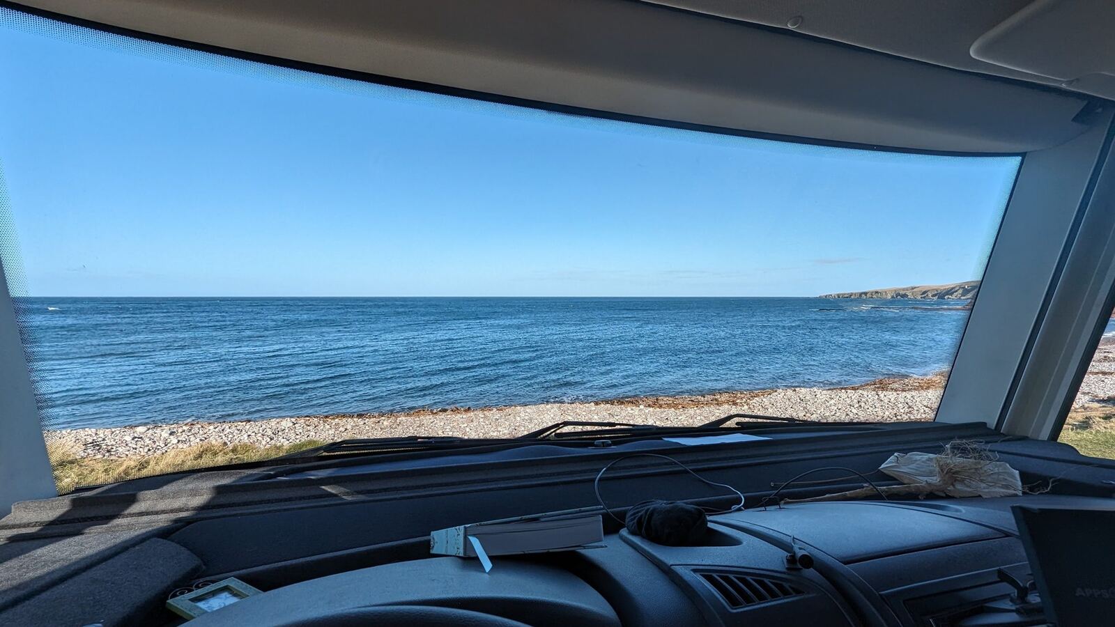 The view over the pebble beach and Moray Firth from inside the campervan at Aberdour Bay.