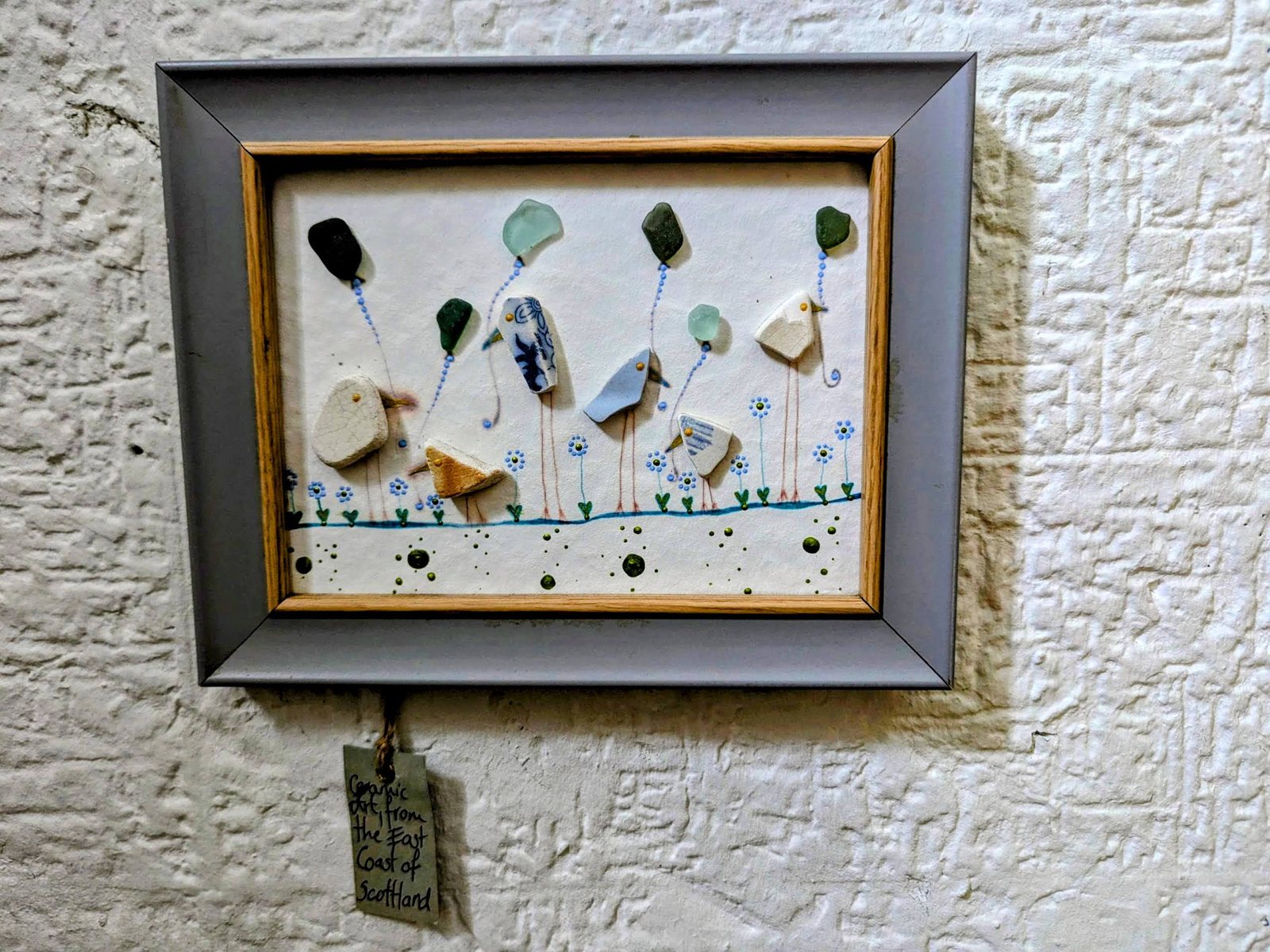 Framed picture of birds made from sea glass and pottery beach finds, tagged Ceramic Art from the East Coast of Scotland.