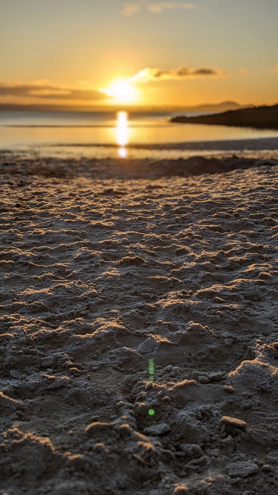 Sea-smoothed pebbles and stones on the shore at Aberdour in golden light.