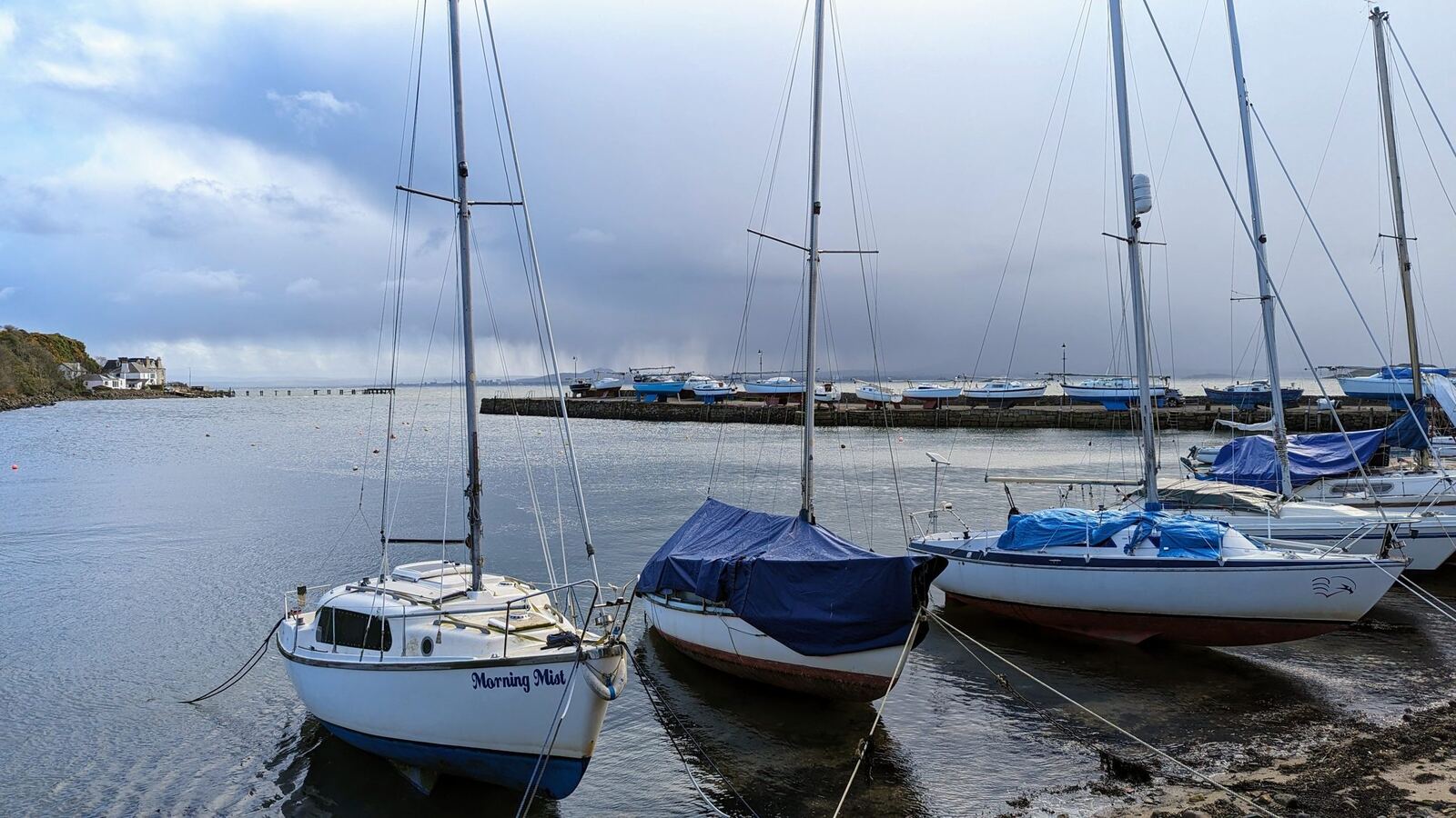 Yachts moored in Aberdour harbour at low tide.