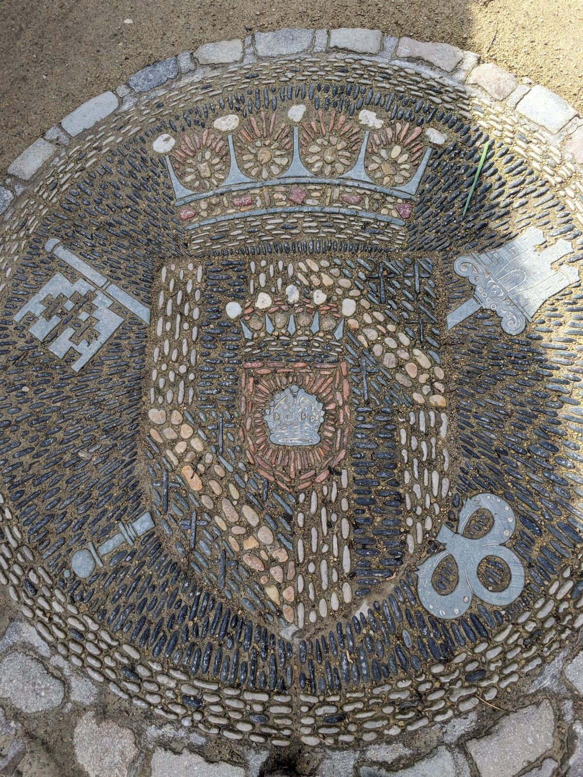 A heraldic mosaic of a crowned shield set into the pavement in Alloa town centre.