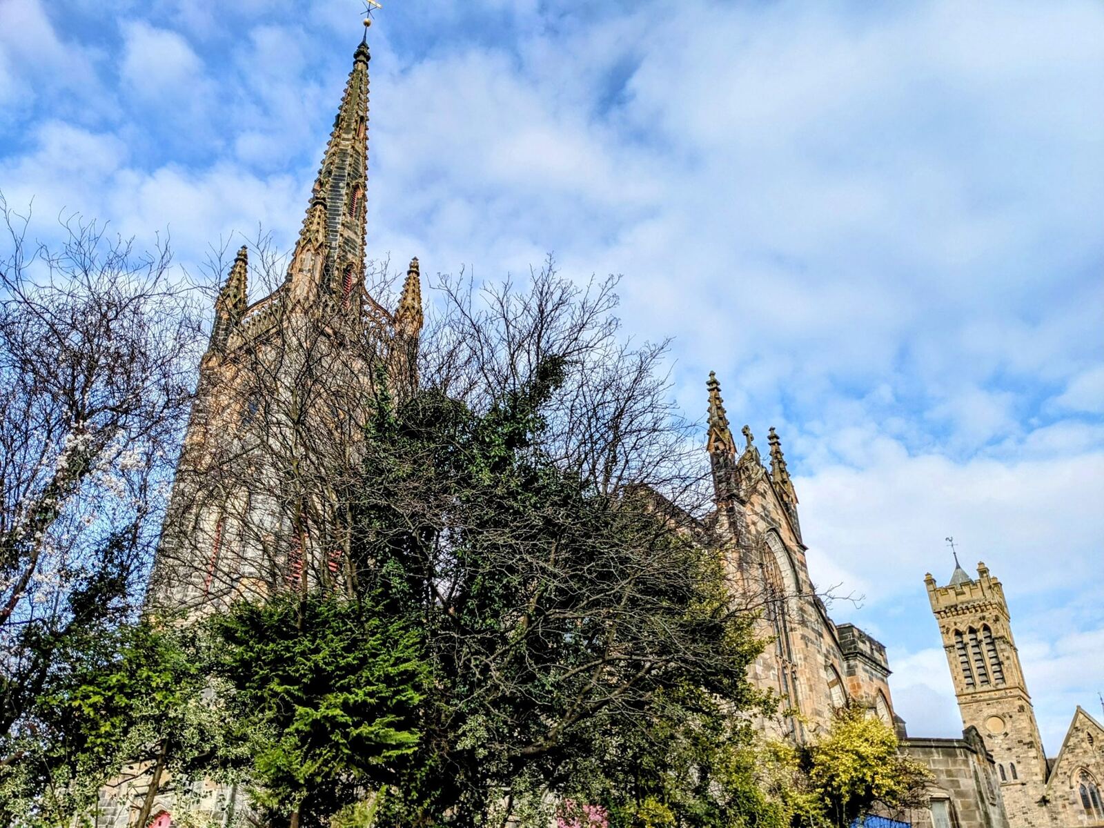 St Mungo's Parish Church in Alloa, its tall Gothic spire rising against a blue sky.