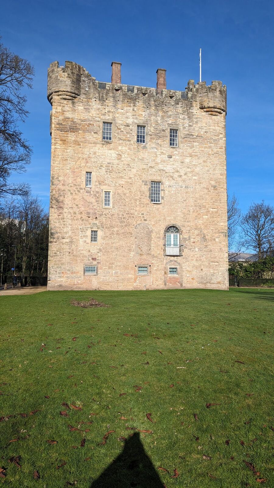 Alloa Tower, a huge medieval stone keep, standing on green lawn under a blue sky.