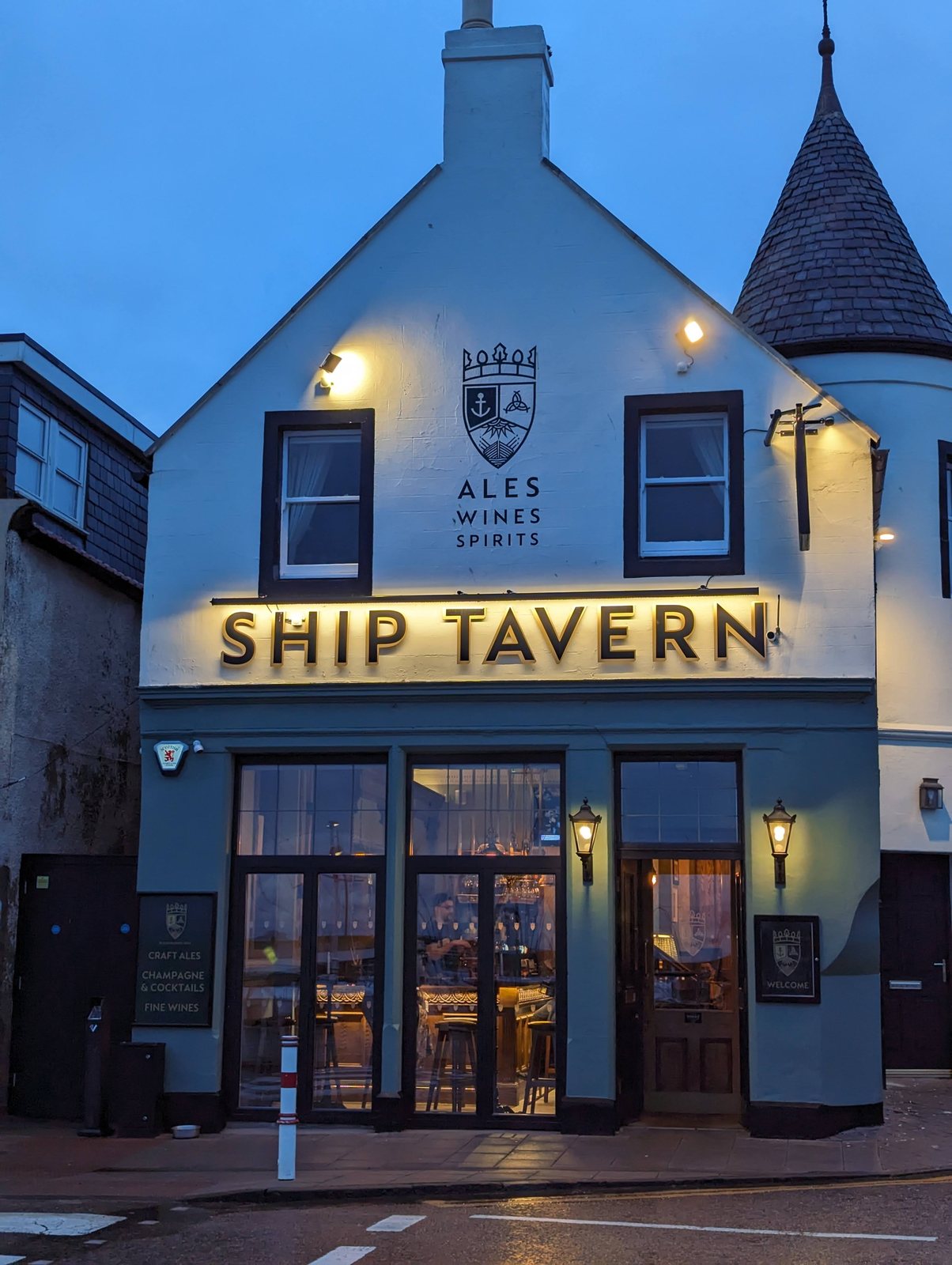 The Ship Tavern lit up at dusk on the Anstruther shore.