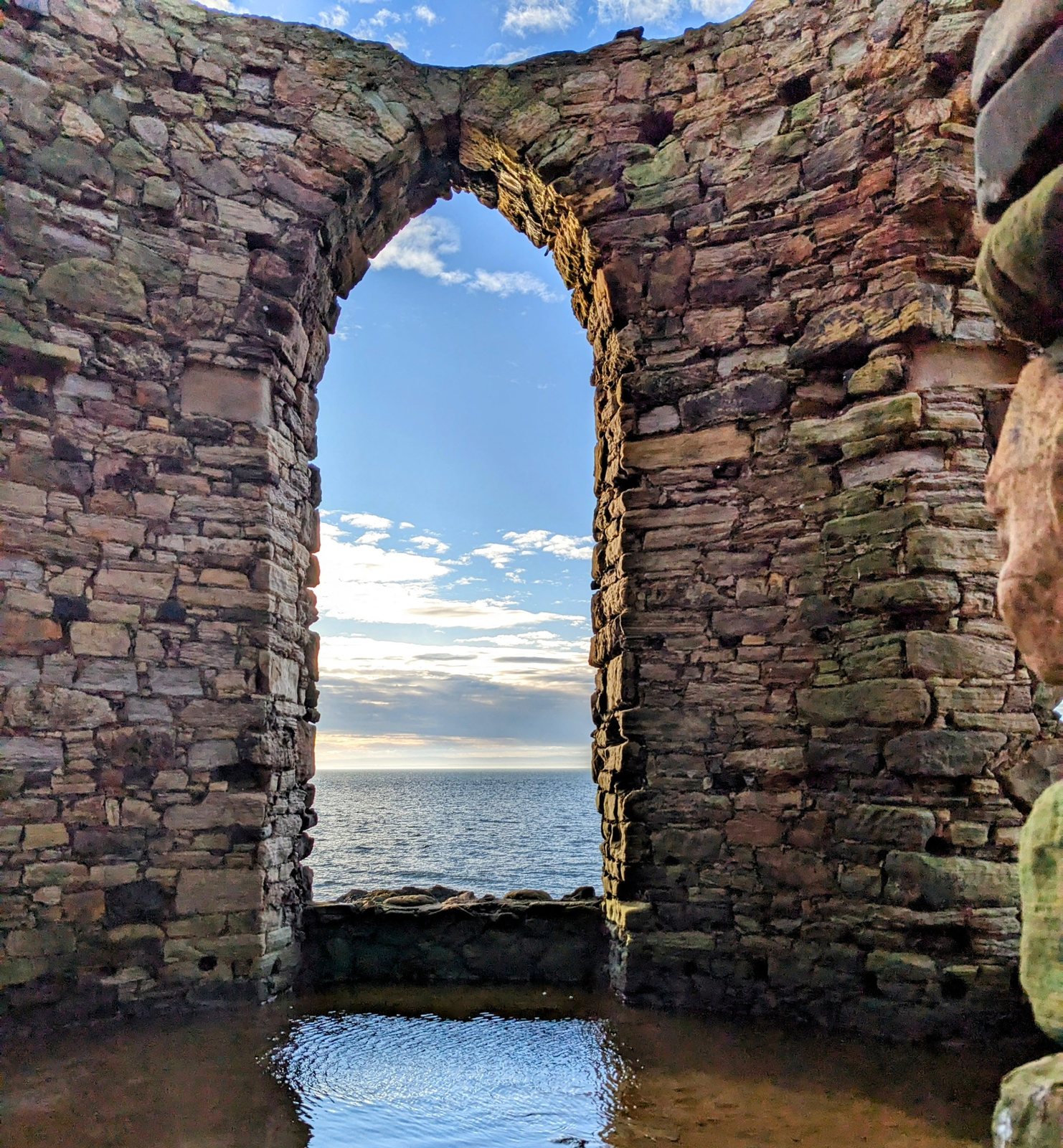 Sunrise through the great arch of a roofless shore tower at Anstruther.