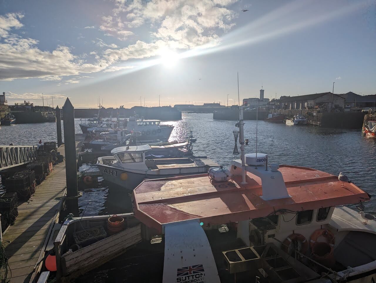 A fishing boat in Arbroath harbour with the sun low over the water.