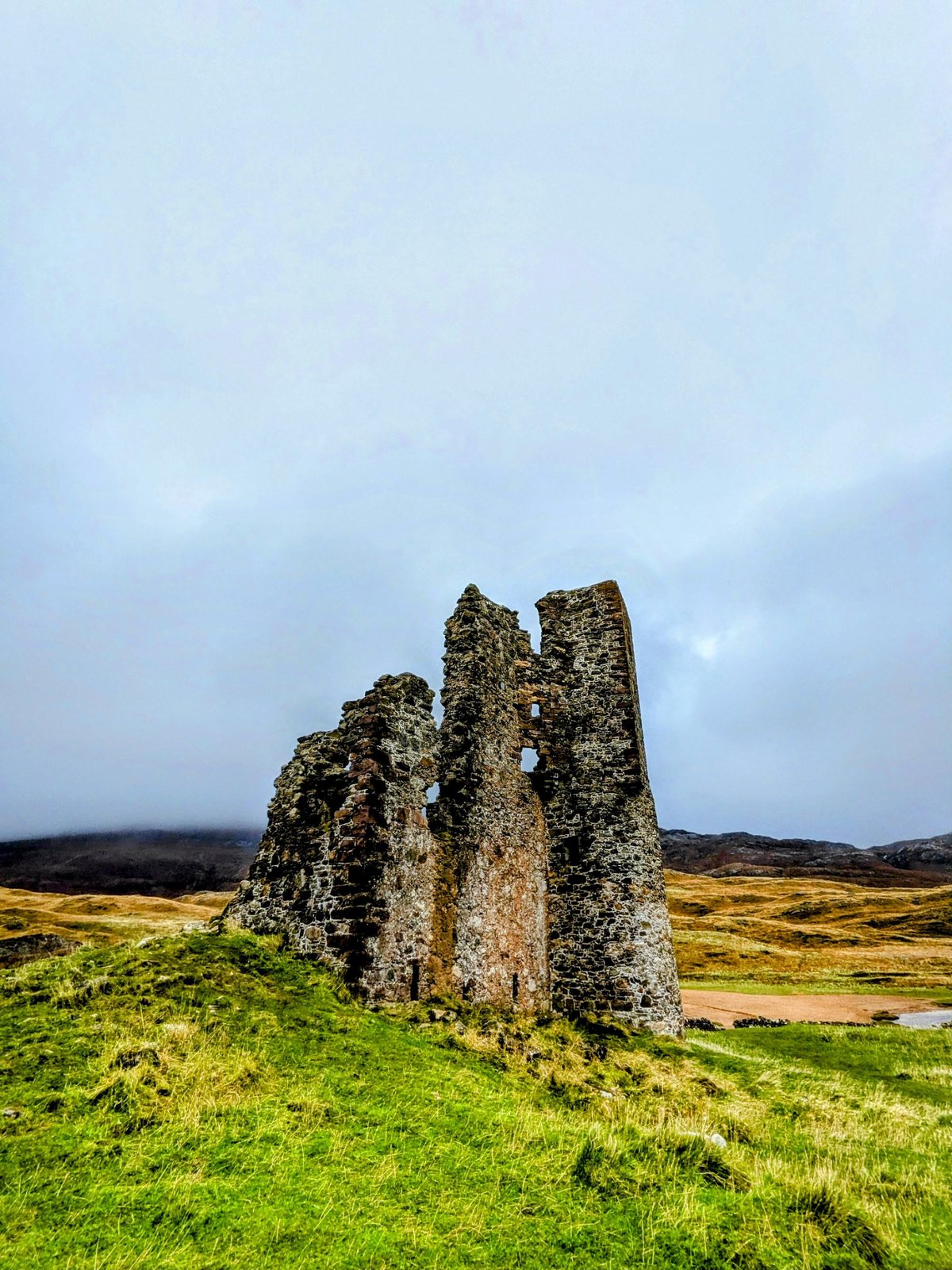 The jagged ruin of Ardvreck Castle against a stormy sky.