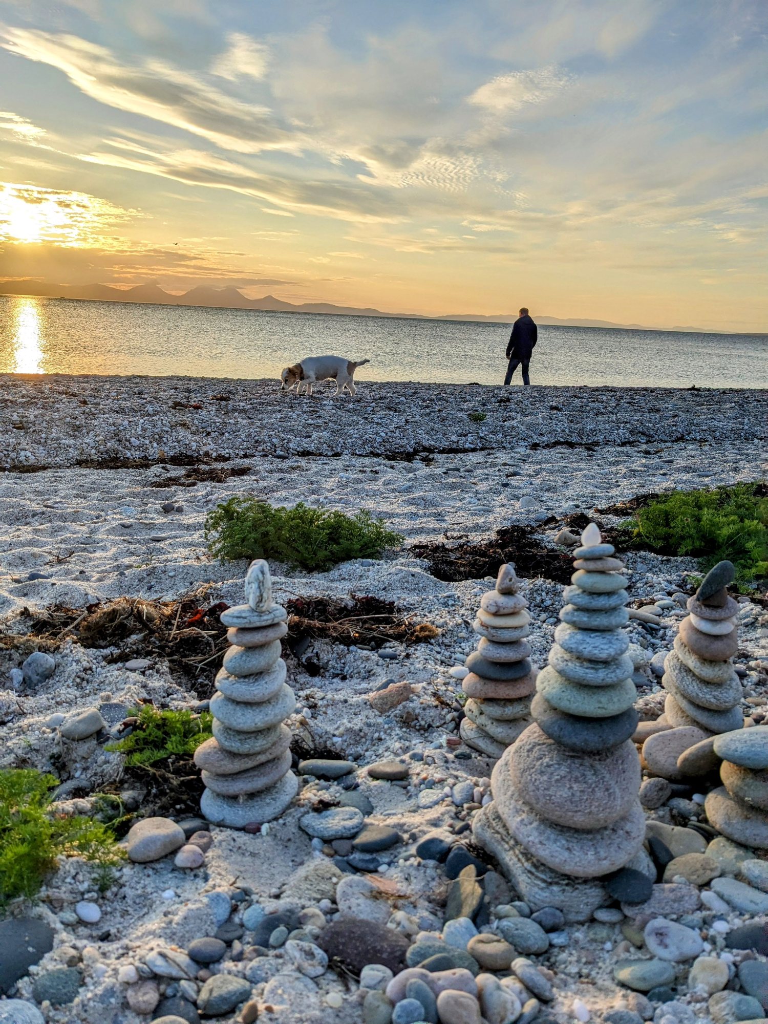 Sunset over the sea at Ballochroy on the west Kintyre coast, with stacked stones on the shingle.