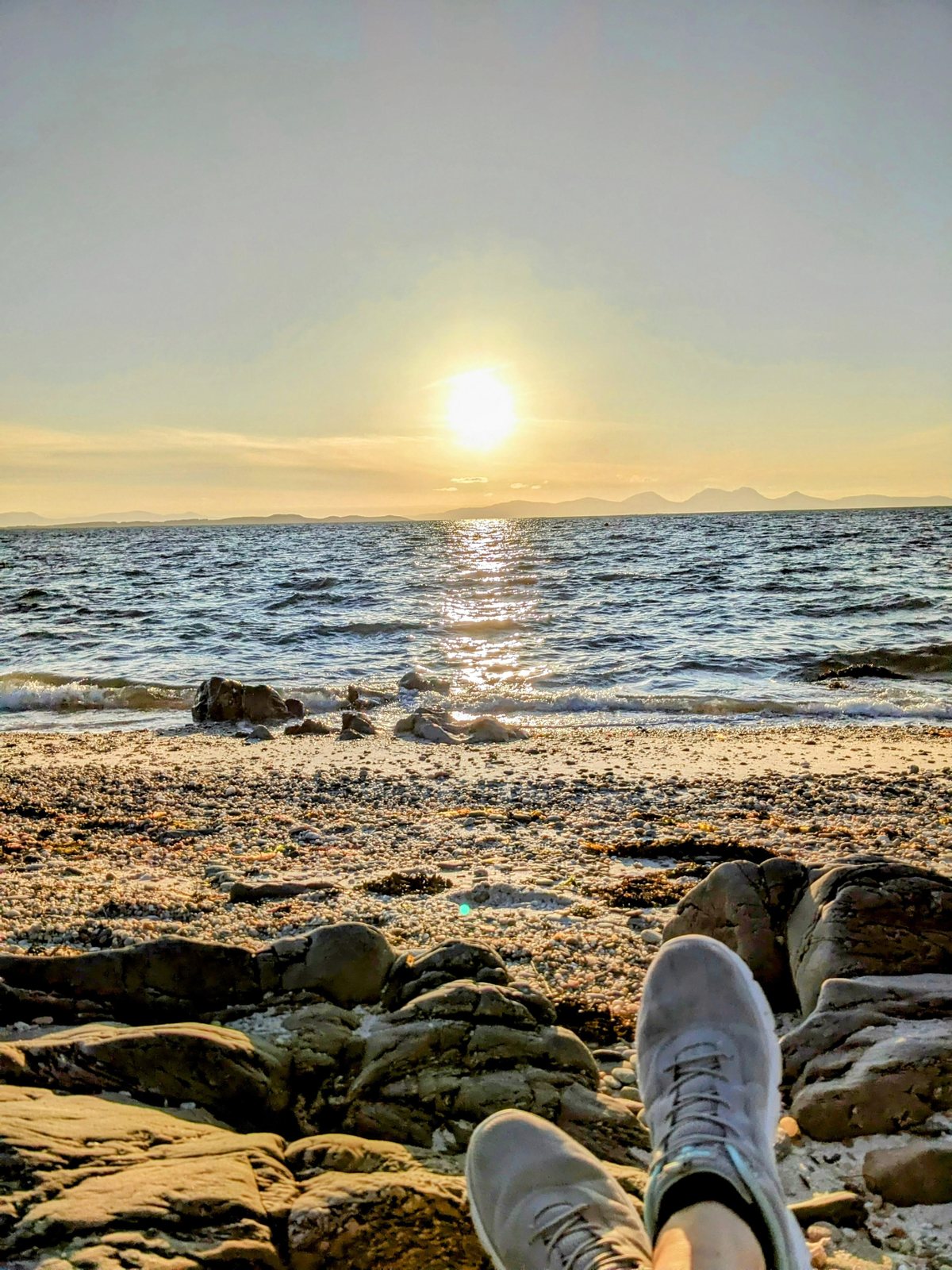Feet up on the shingle watching the sunset at Ballochroy.