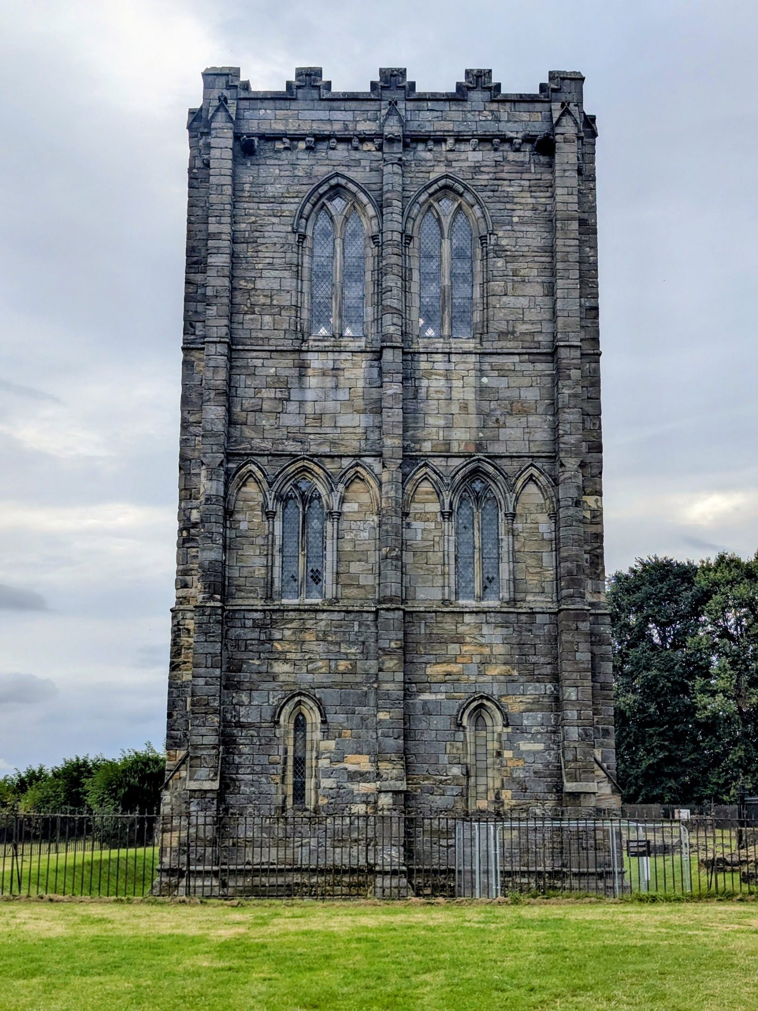 The tall medieval free-standing bell tower of Cambuskenneth Abbey standing alone in green meadows near Stirling.