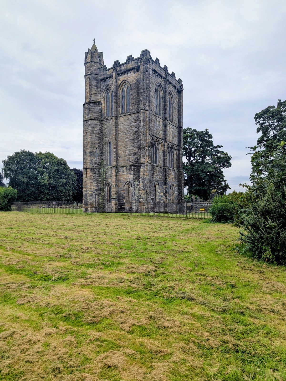 Cambuskenneth Abbey tower rising from a green mound that hides the foundations of the abbey church.