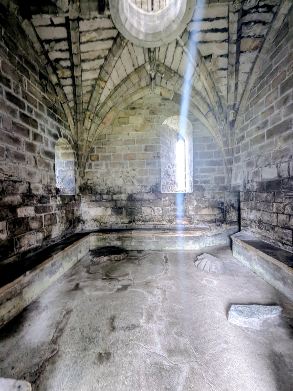 The ribbed stone vault inside the ground floor of Cambuskenneth Abbey tower, lit by a shaft of light.