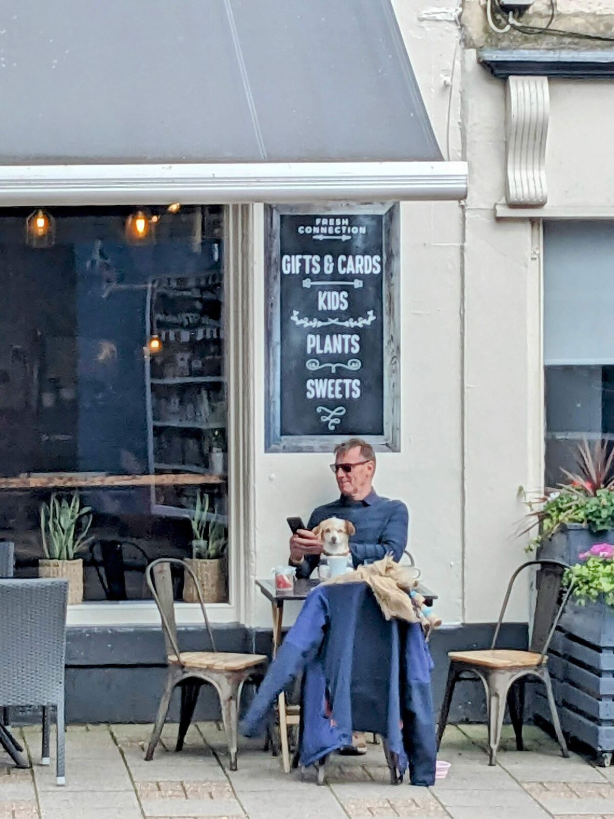 A man and a small dog at an outdoor table outside The Fresh Connection coffee shop in Campbeltown.