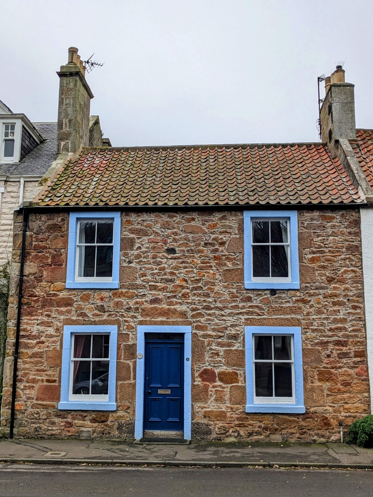 A pantiled Crail cottage with crow-stepped gable and a blue door.