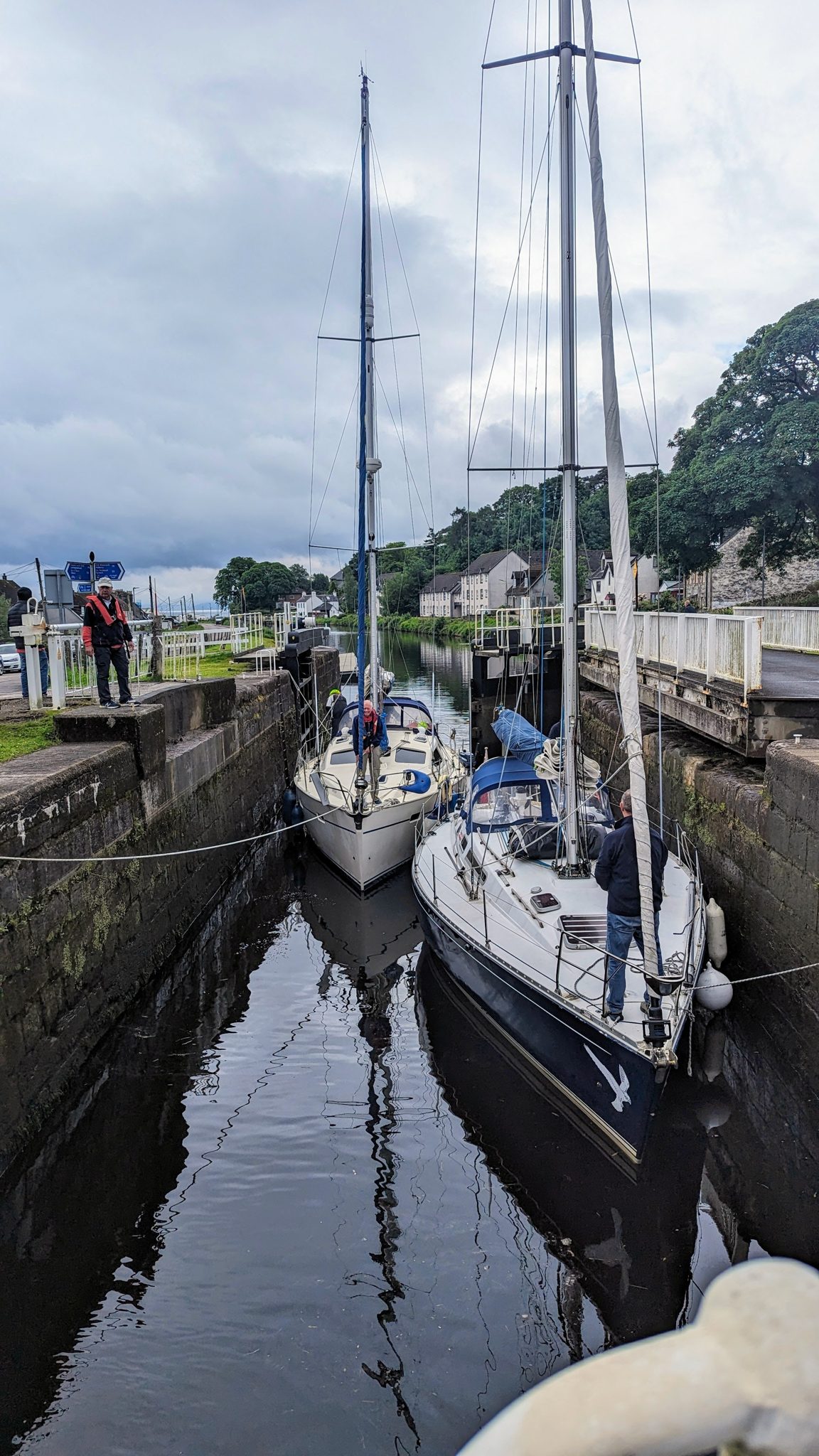 A yacht sitting in a lock chamber on the Crinan Canal with a crew member on the lockside.