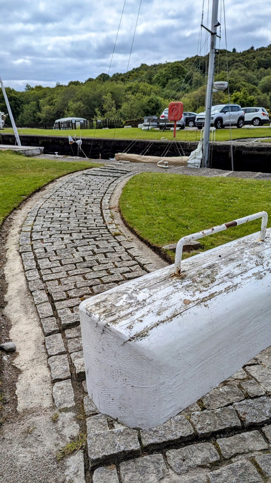 A white-painted lock balance beam and the cobbled path beside it on the Crinan Canal.