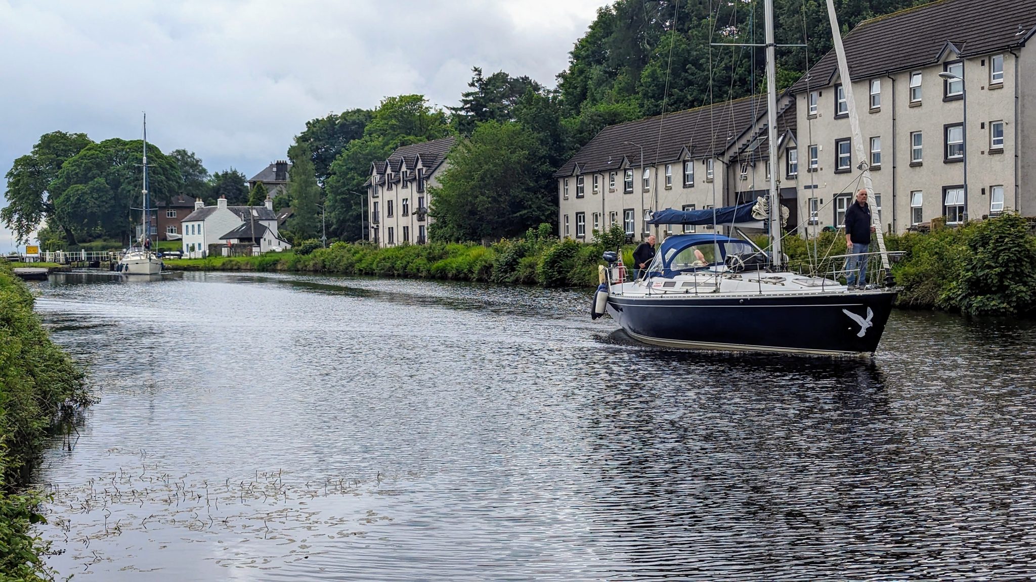 A yacht on the canal basin at Ardrishaig with terraced buildings alongside.