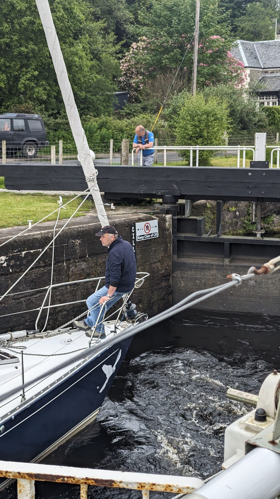 A yacht crew member working a lock rope beside the open gates on the Crinan Canal.