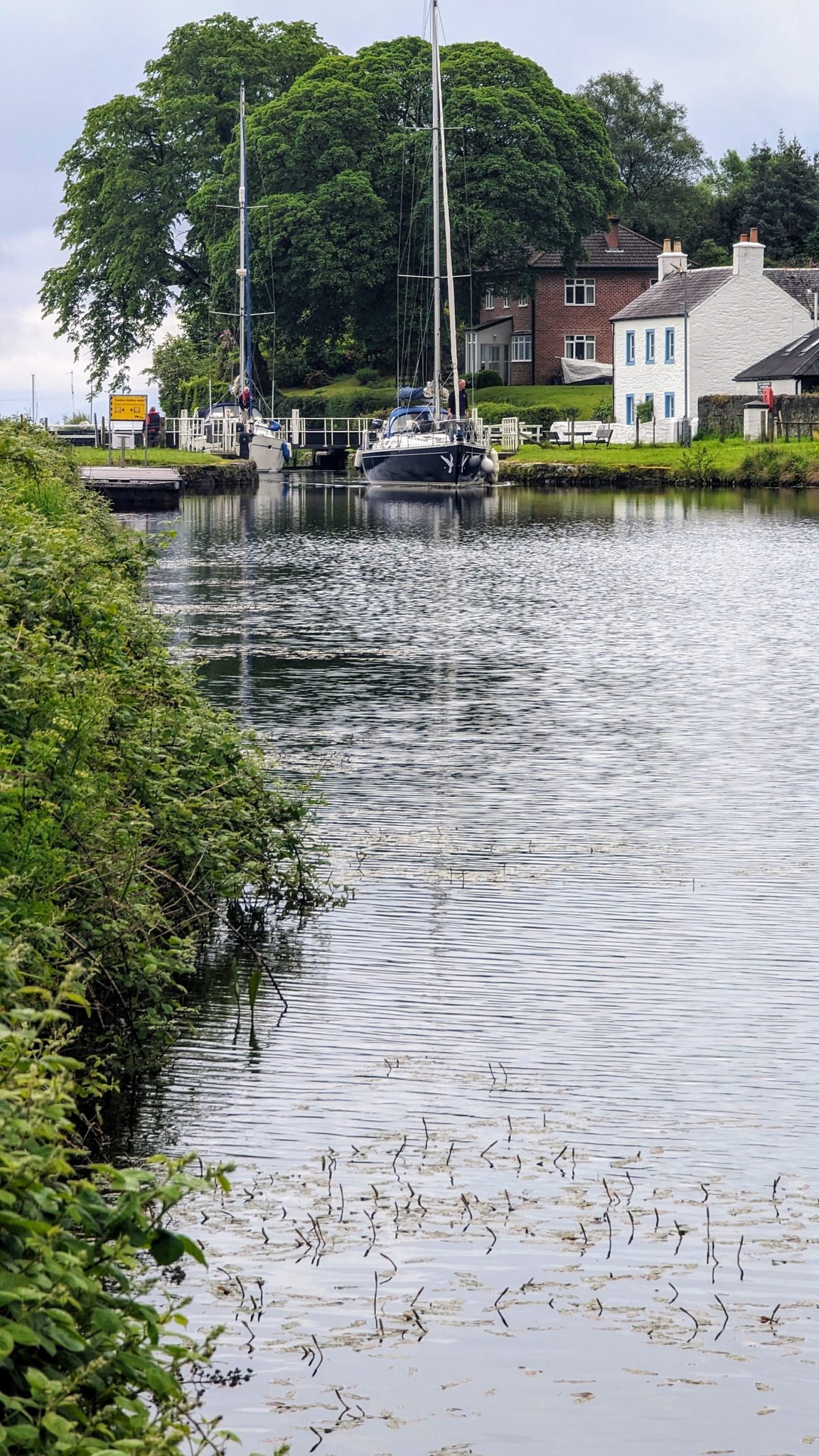 A quiet lock and moored boats reflected in the still water of the Crinan Canal.