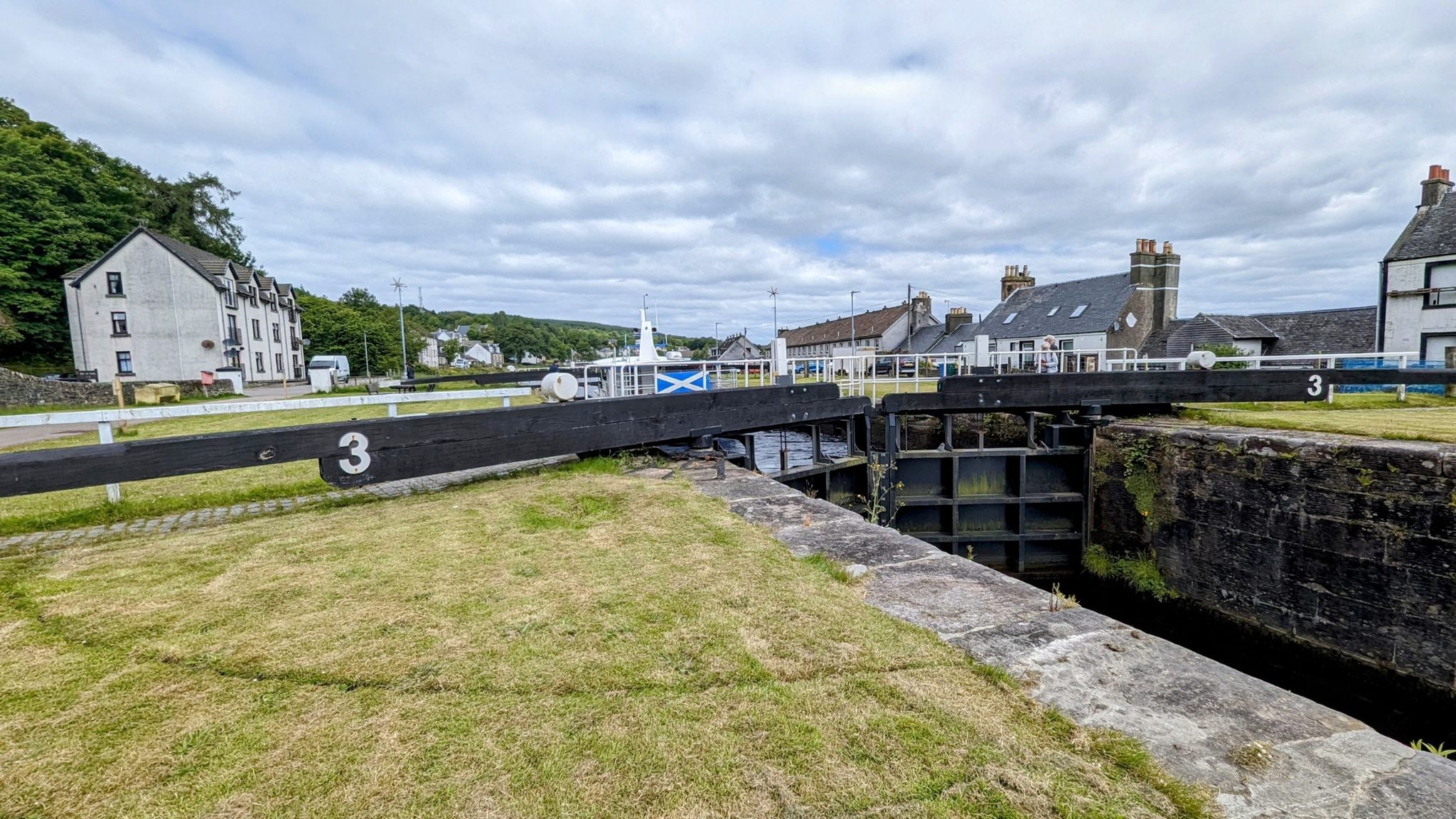 A flight of numbered locks stepping up the Crinan Canal, a Saltire flying beyond.
