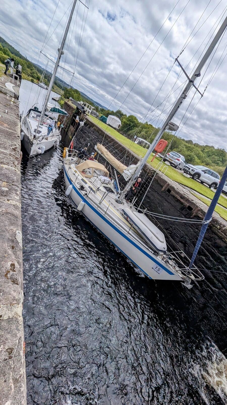 A yacht sitting low inside a stone lock chamber on the Crinan Canal, waiting for the water to rise.