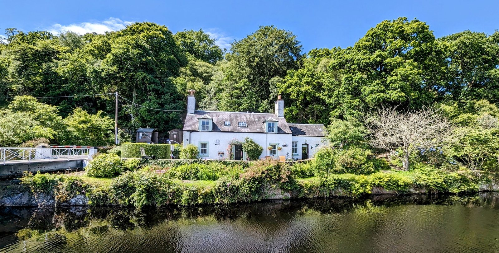 Whitewashed cottages tucked among trees above the water at Crinan.