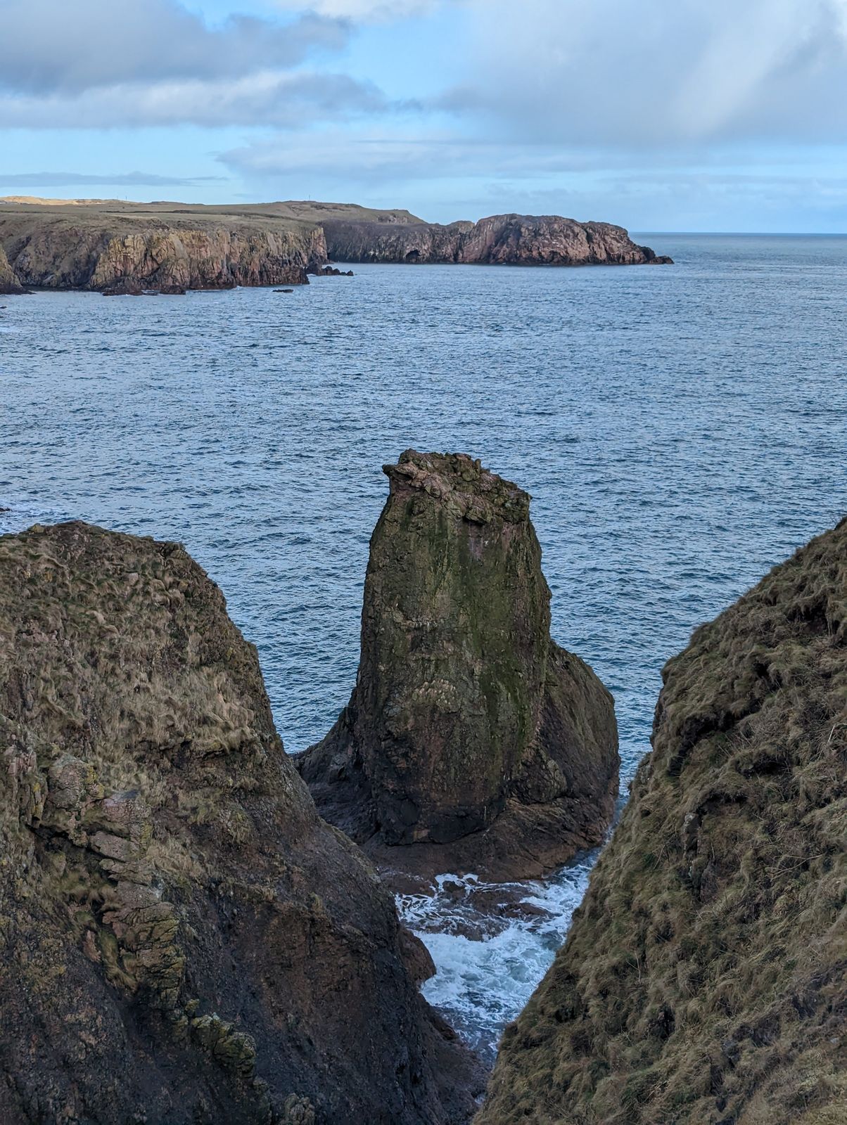 A tall sea stack rising from the water on the cliffs near Cruden Bay.