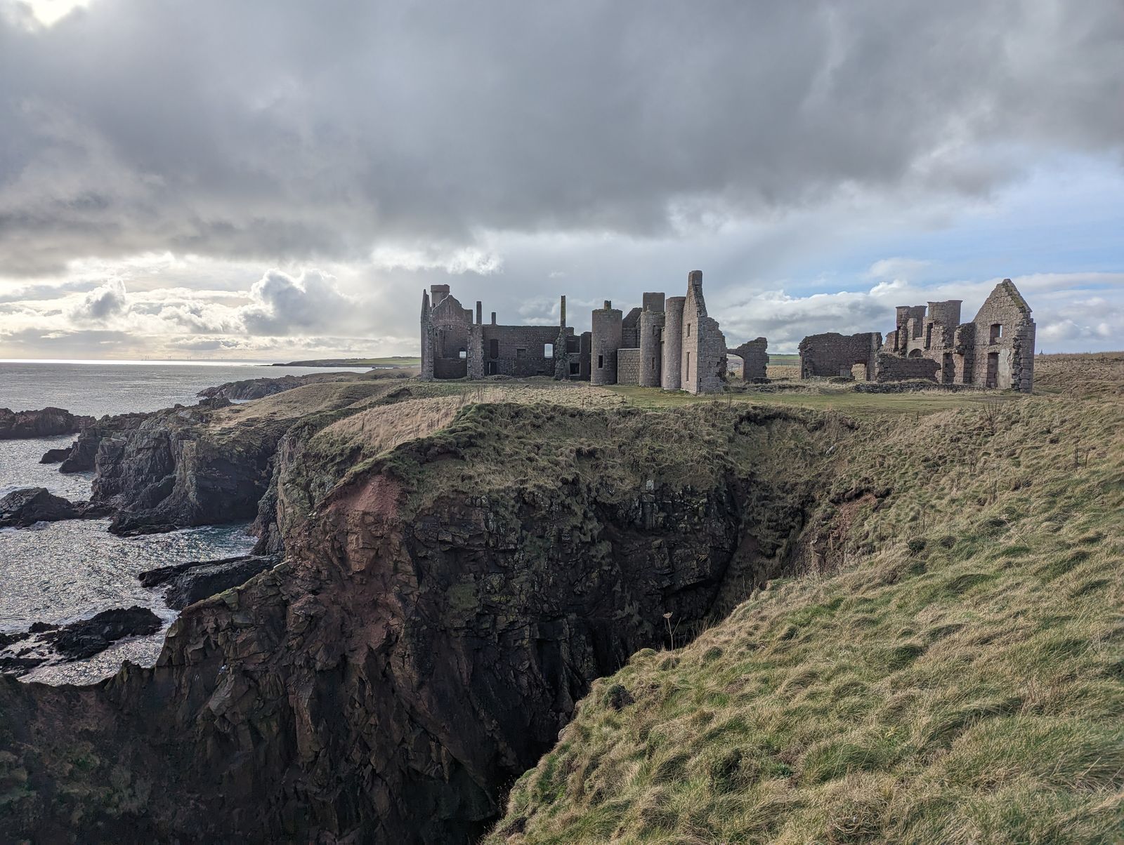 The classic profile of Slains Castle across a deep rocky geo.