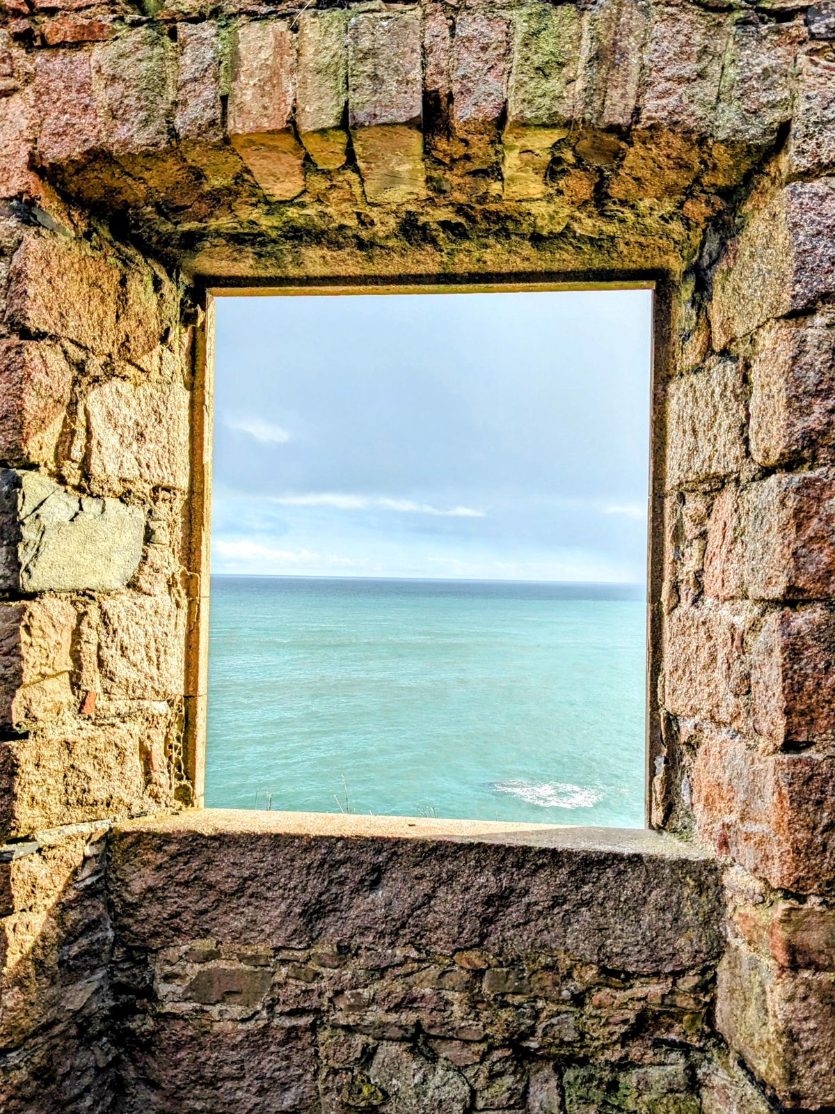 A ruined window of Slains Castle framing nothing but the open North Sea.