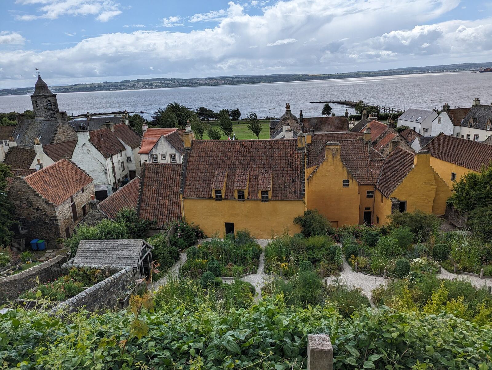 The view over Culross rooftops and the ochre Culross Palace and its terraced garden, the Firth of Forth beyond.