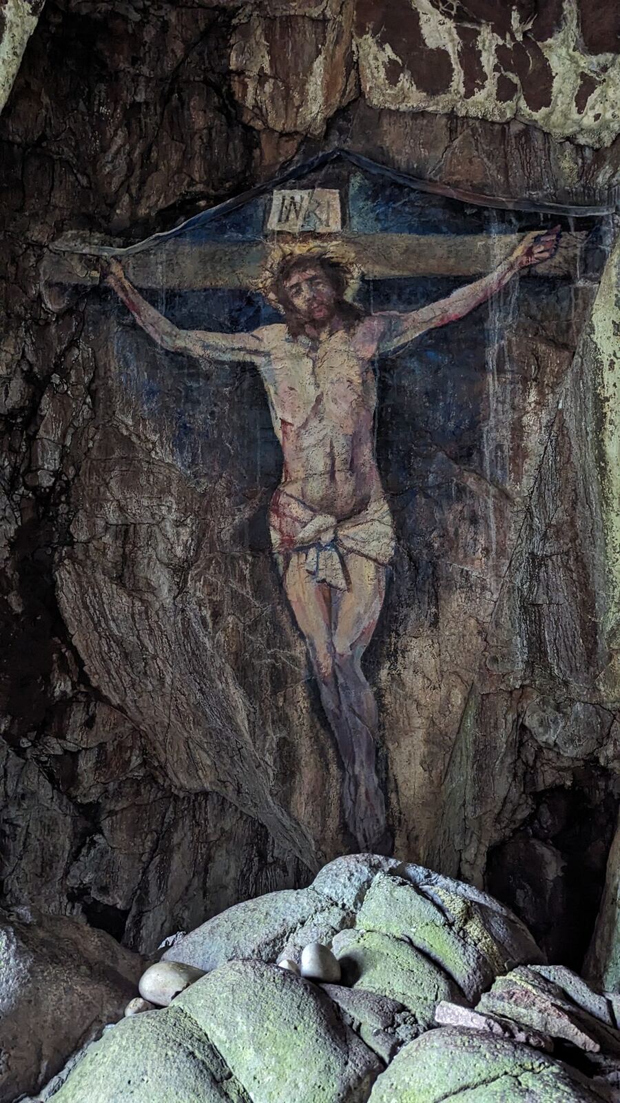 A life-size painting of the crucified Christ on the rock wall inside a sea cave on Davaar Island.