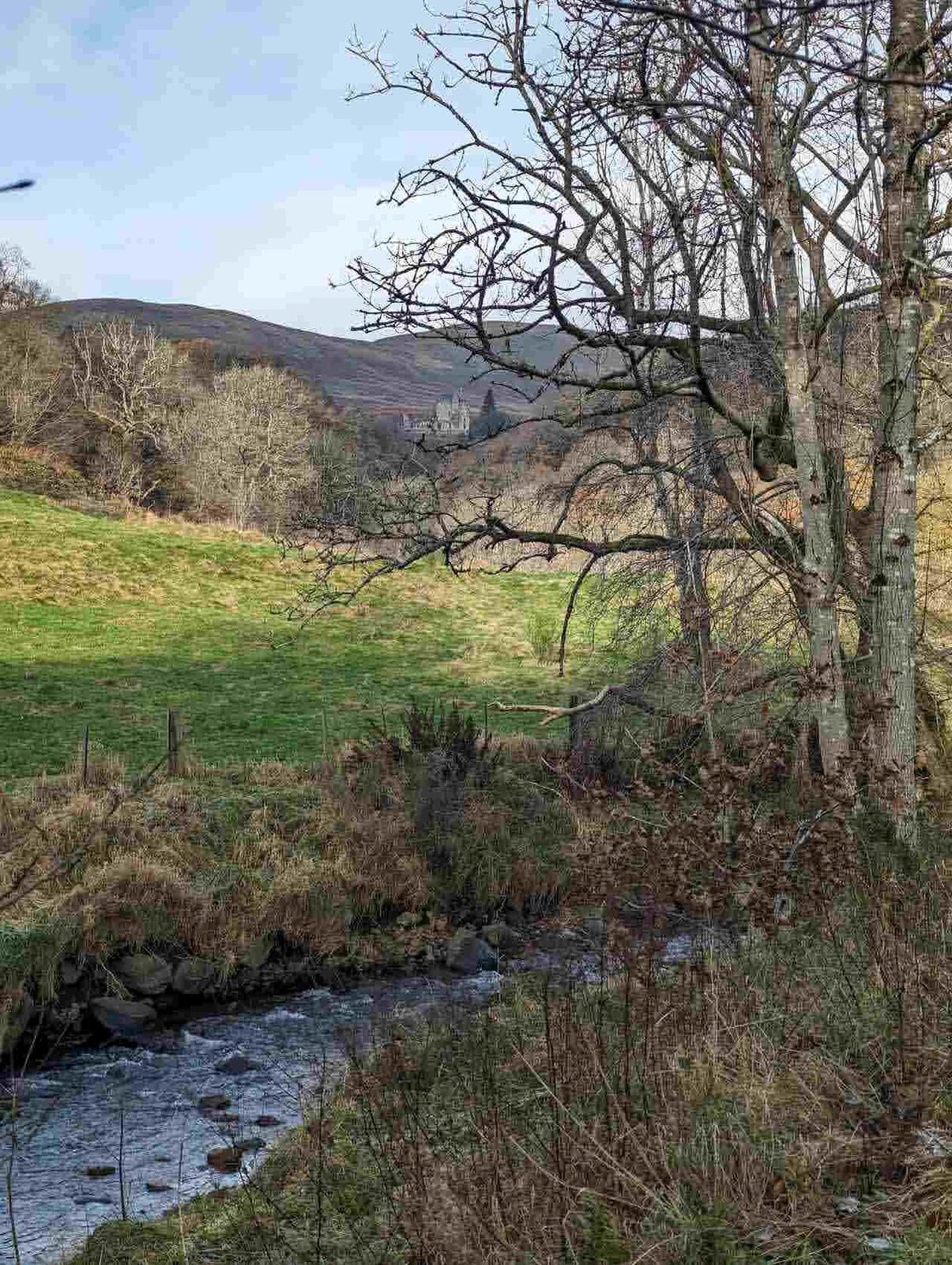 The Dollar Burn running between grassy banks with the Ochil Hills beyond.