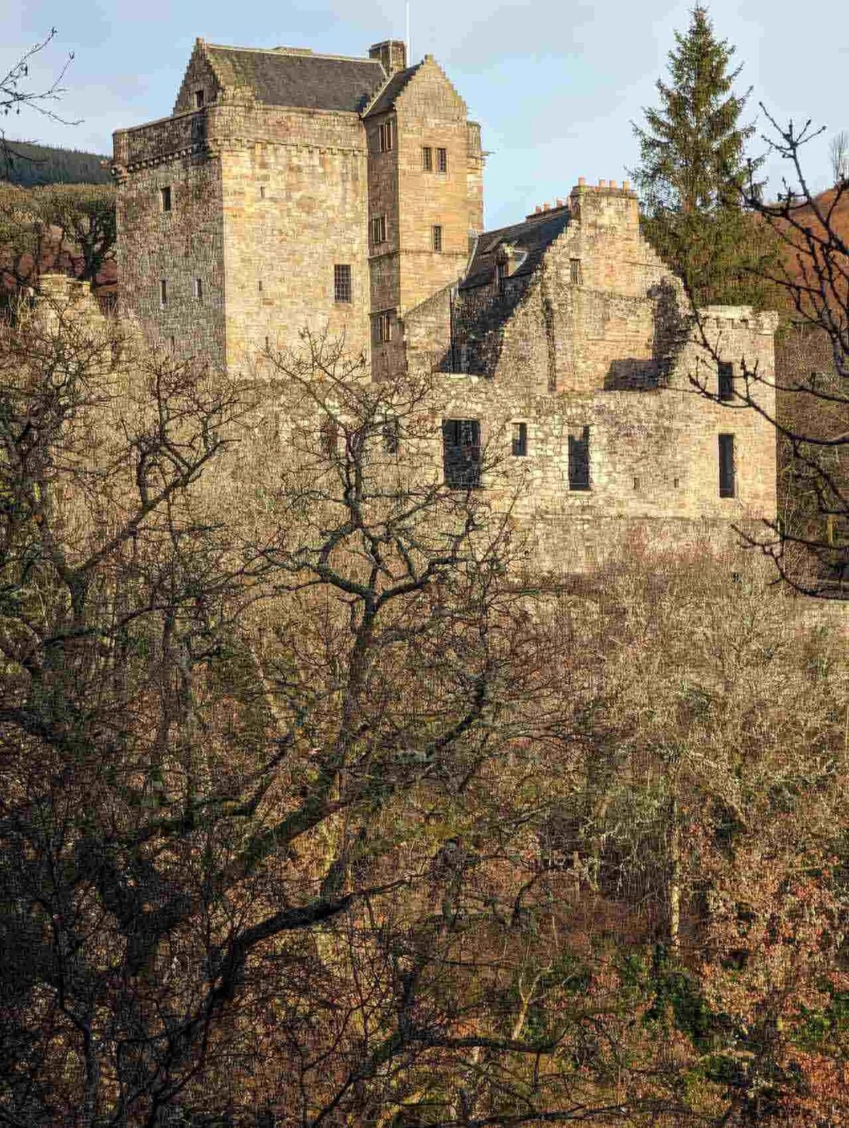 The ruined ranges and tower house of Castle Campbell against a blue sky.