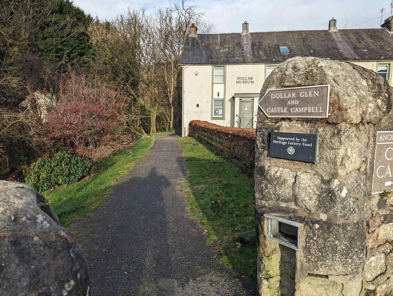 The lane out of Dollar past a white cottage, with the signpost for Dollar Glen and Castle Campbell