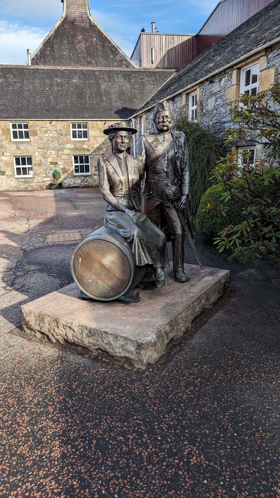 A bronze statue of two Highland figures with a whisky cask outside a Dufftown distillery.