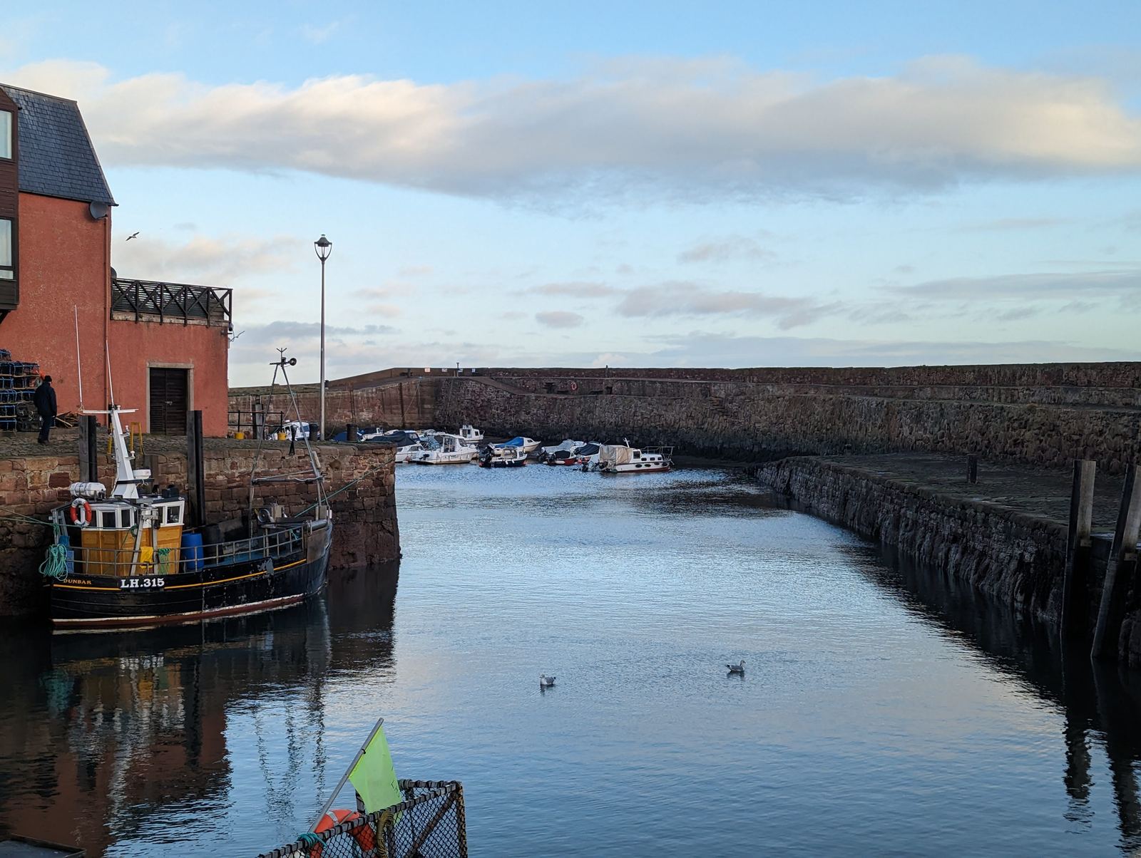 Dunbar's harbour ringed by red sandstone buildings, fishing boats on the water.