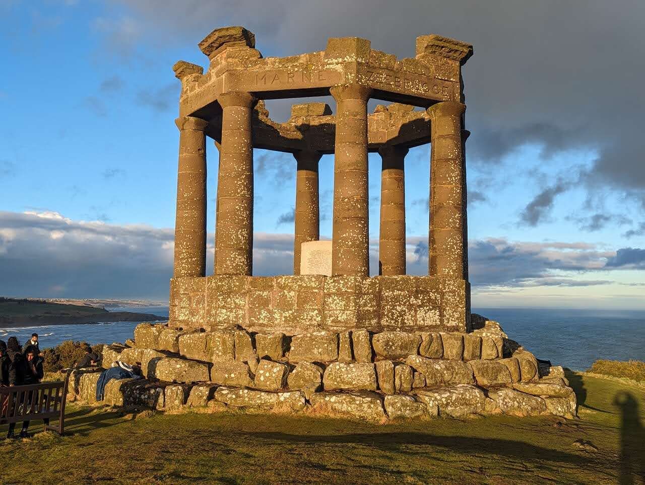 The roofless colonnade of the Stonehaven War Memorial above the sea.