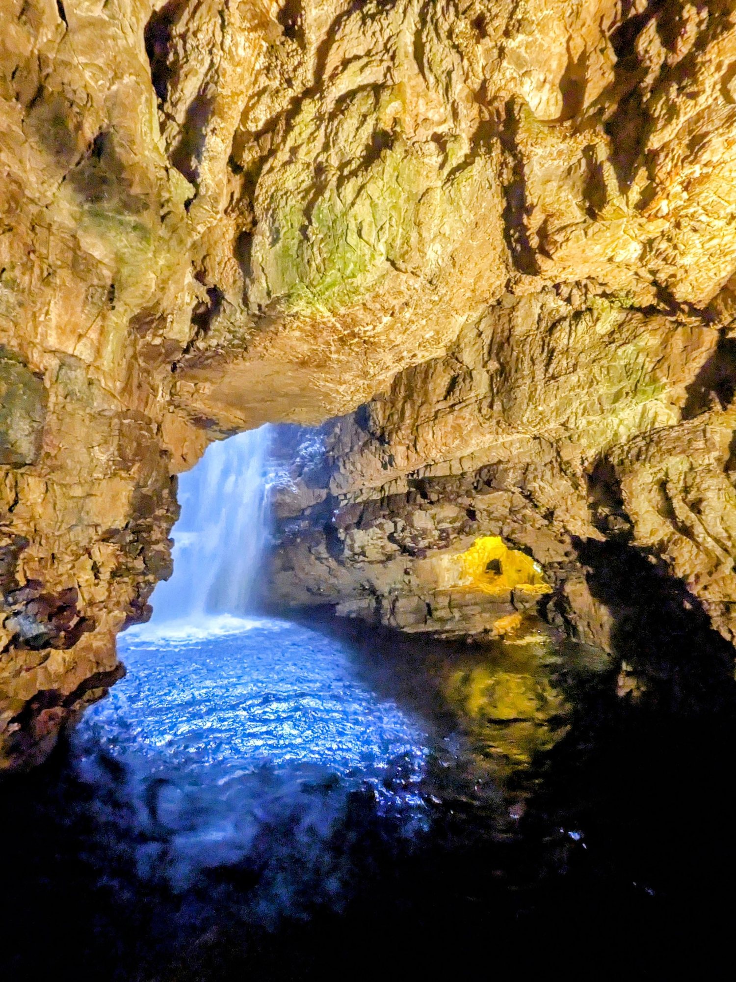 The waterfall inside Smoo Cave near Durness, lit blue.