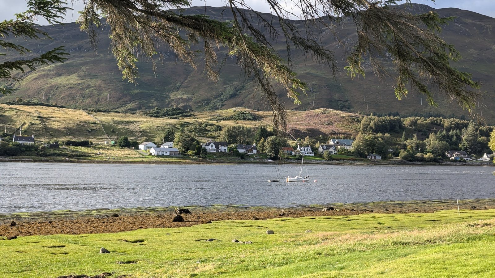 Eilean Donan Castle seen across the loch with hills behind.