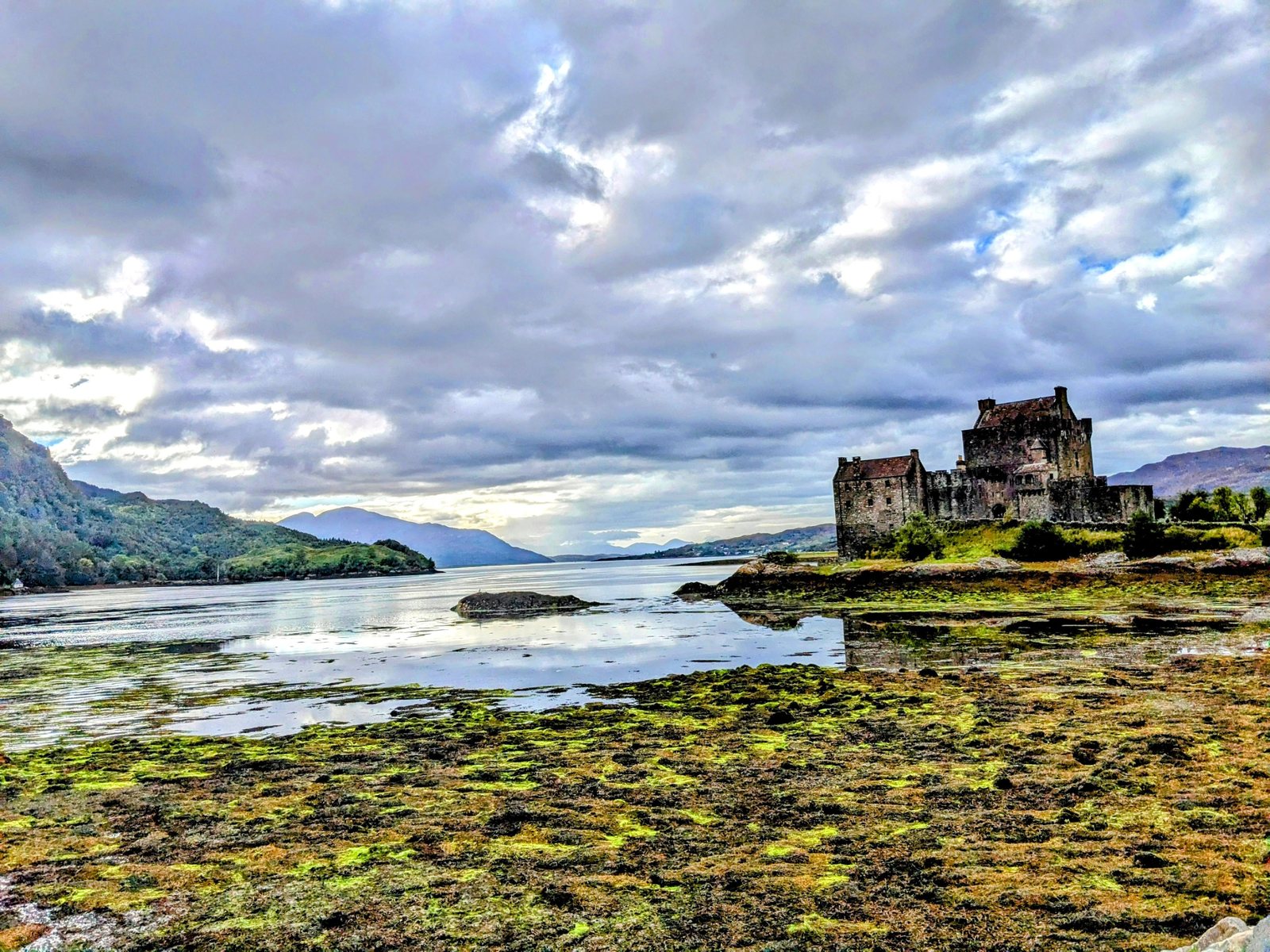 Eilean Donan Castle at low tide with seaweed in the foreground.