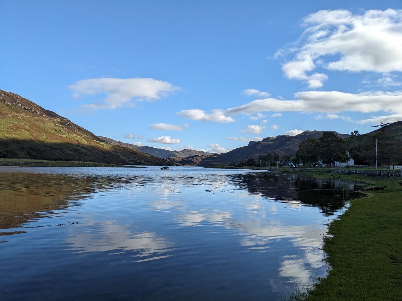 Loch Duich flat calm under a blue sky, the hills mirrored in the water