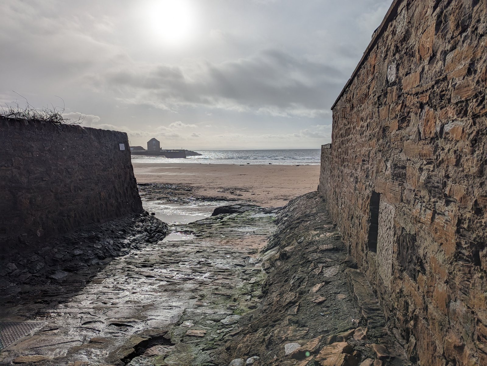 The old harbour wall meeting the beach at Elie.