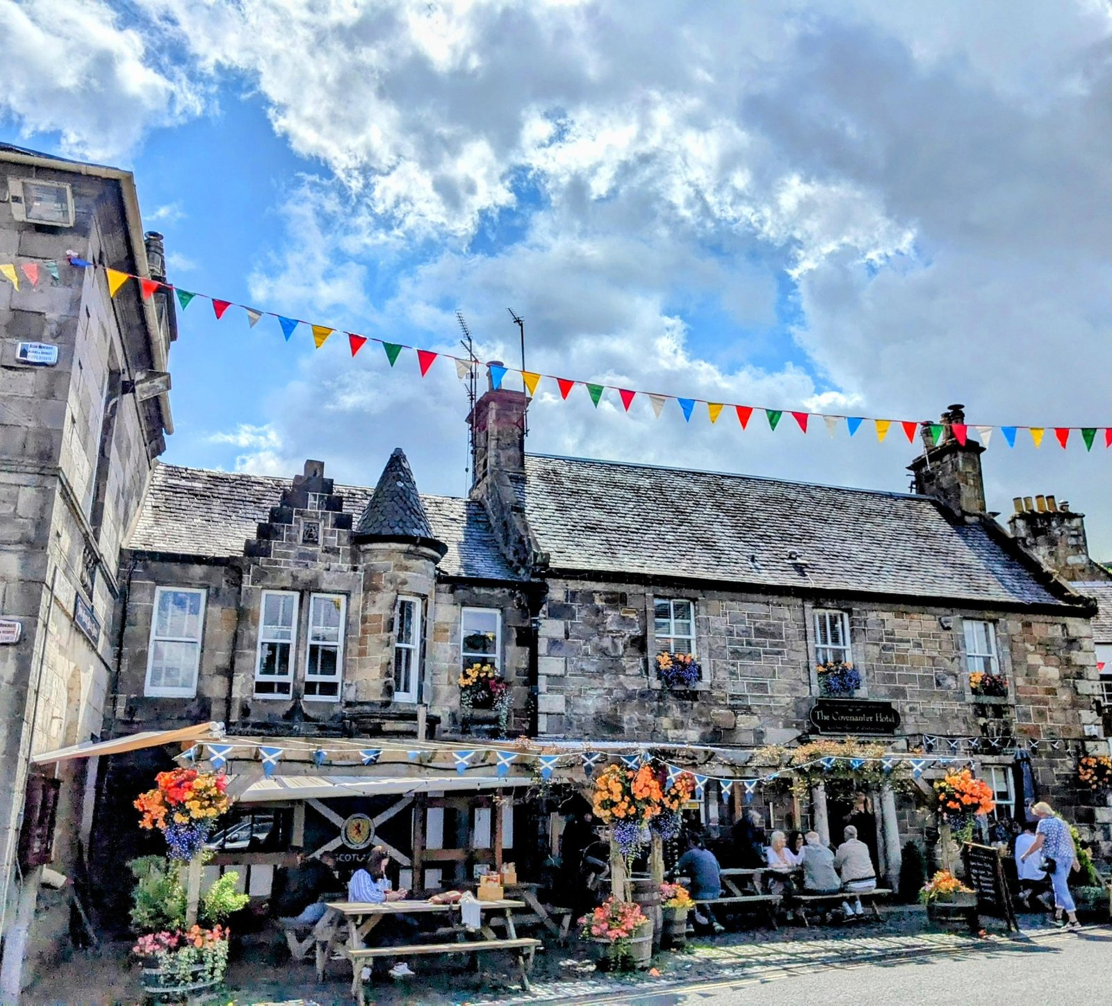 People eating outside a busy cafe with bunting in Falkland.
