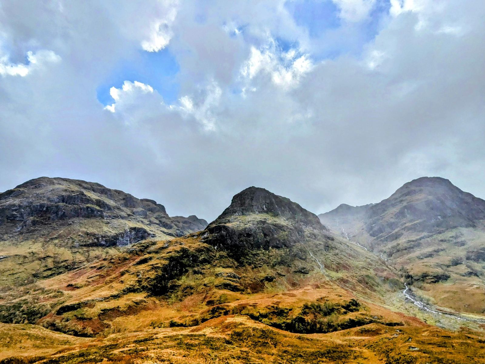 A classic steep pyramidal Highland peak guarding the mouth of Glen Coe under a bright sky.