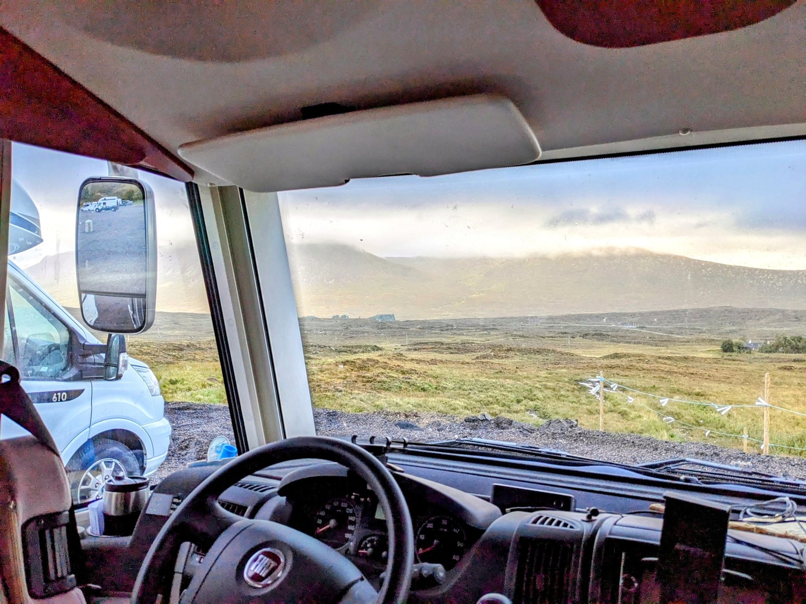 The moody moor and cloud-topped mountains of Glen Coe seen from the motorhome cab.