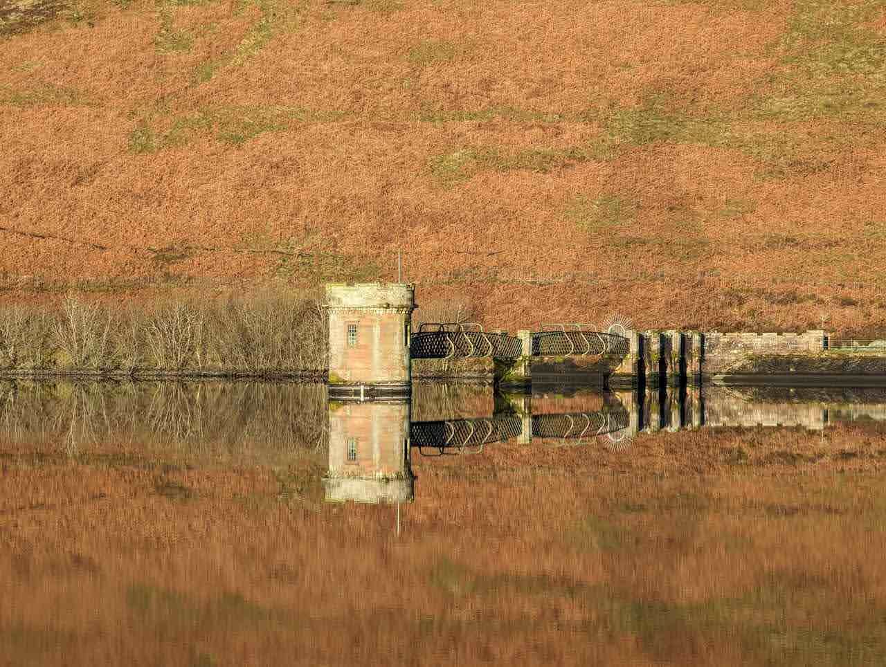 A valve tower mirrored in the still water of a Glendevon reservoir.