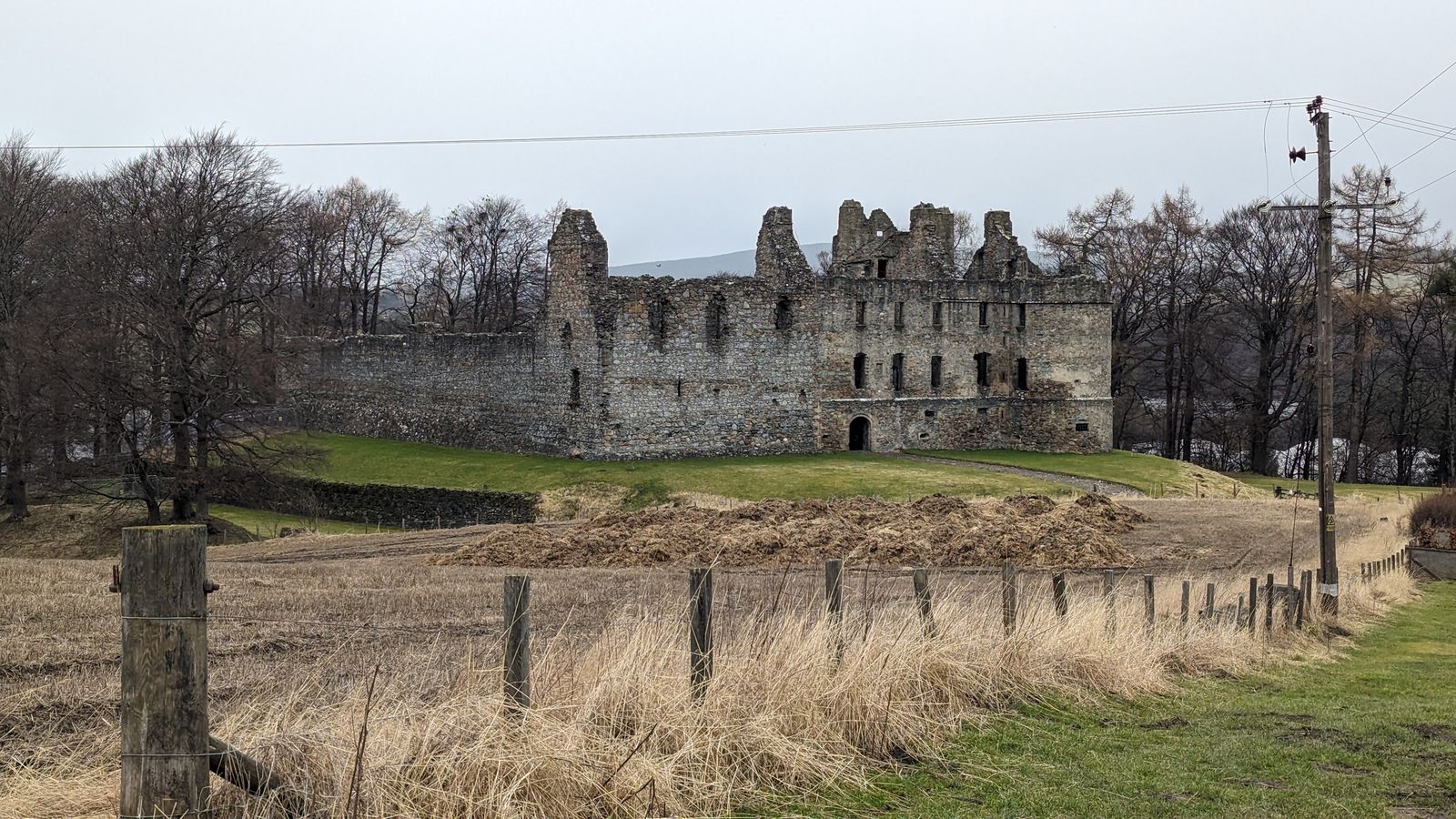 The ruins of Balvenie Castle seen across a stubble field beside Glenfiddich.