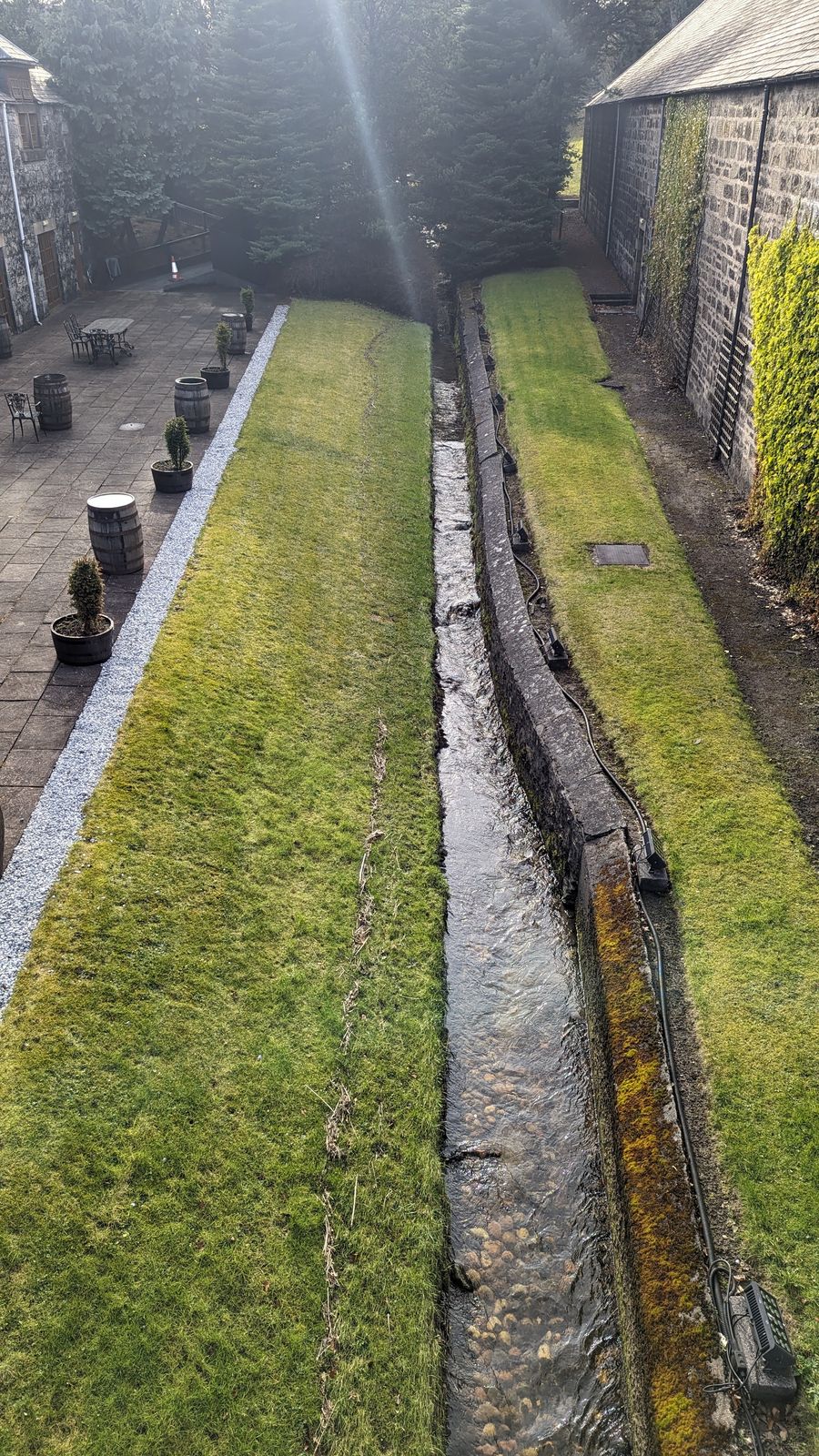 A path and lade running through the green grounds of Glenfiddich Distillery.