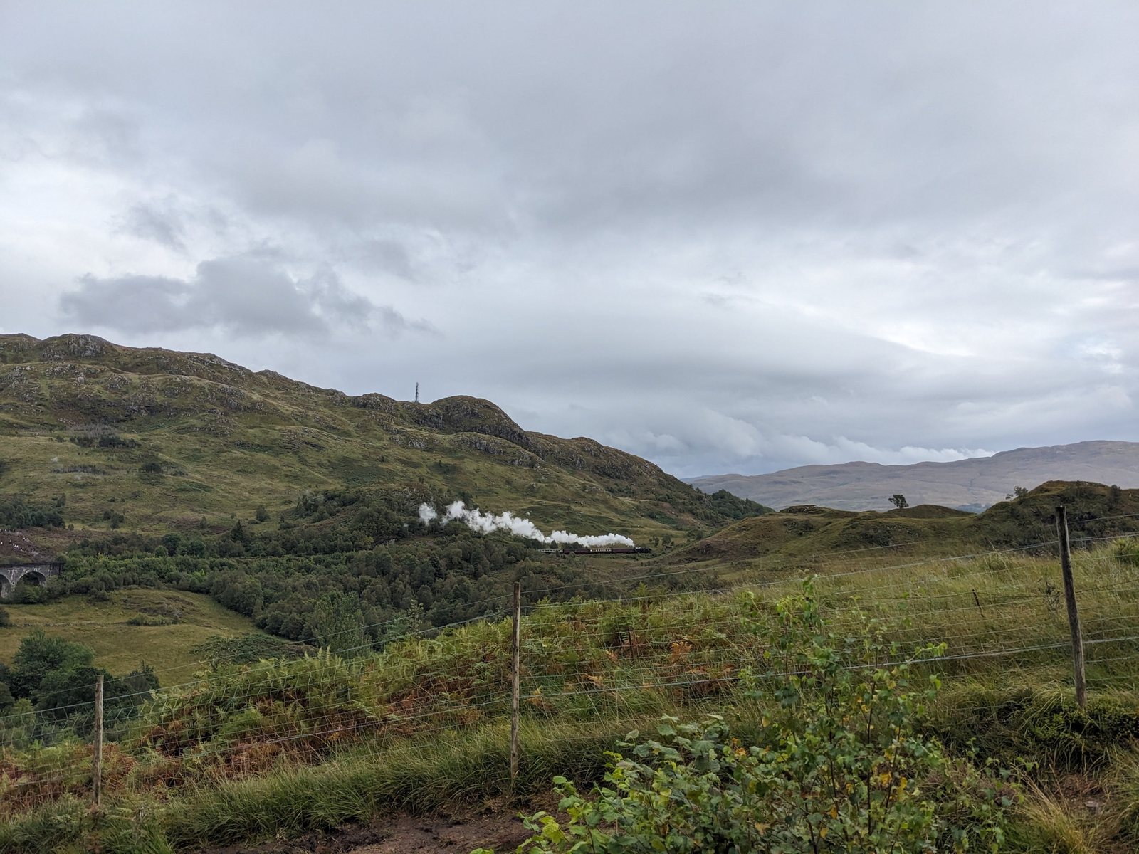 A train crossing the glen at Glenfinnan seen from a distance.